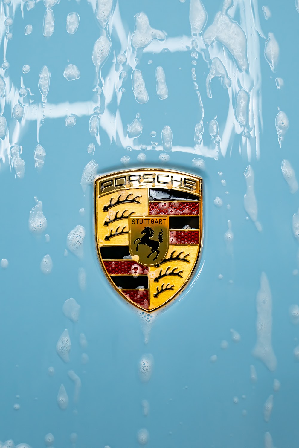 Porsche crest mid-wash during a decontamination detail