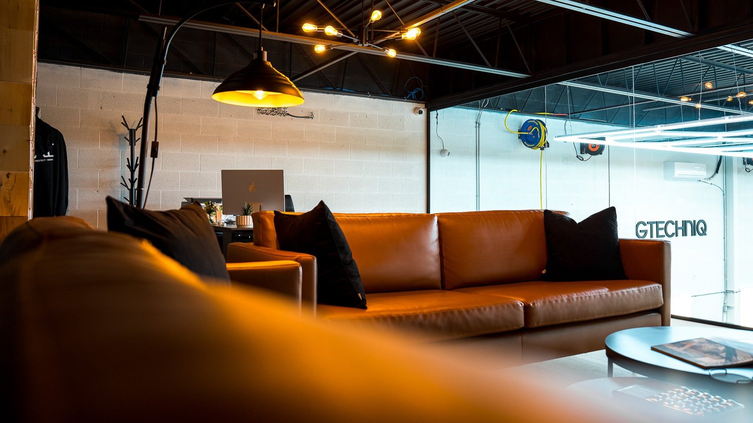 ZAutoCare's elevated client lounge with a glass-wall vantage overlooking the detailing work floor
