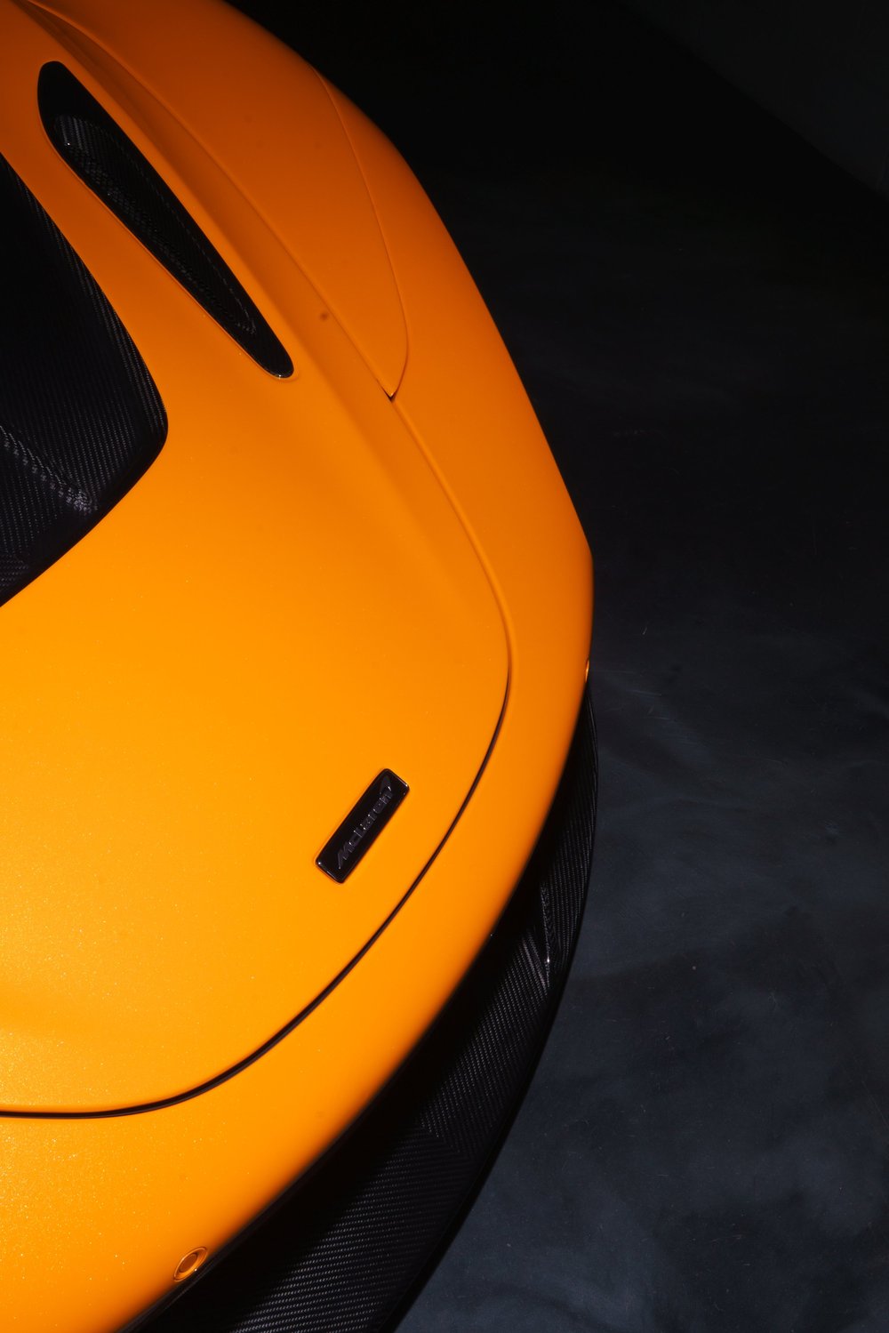 Front badge and carbon splitter of a yellow McLaren