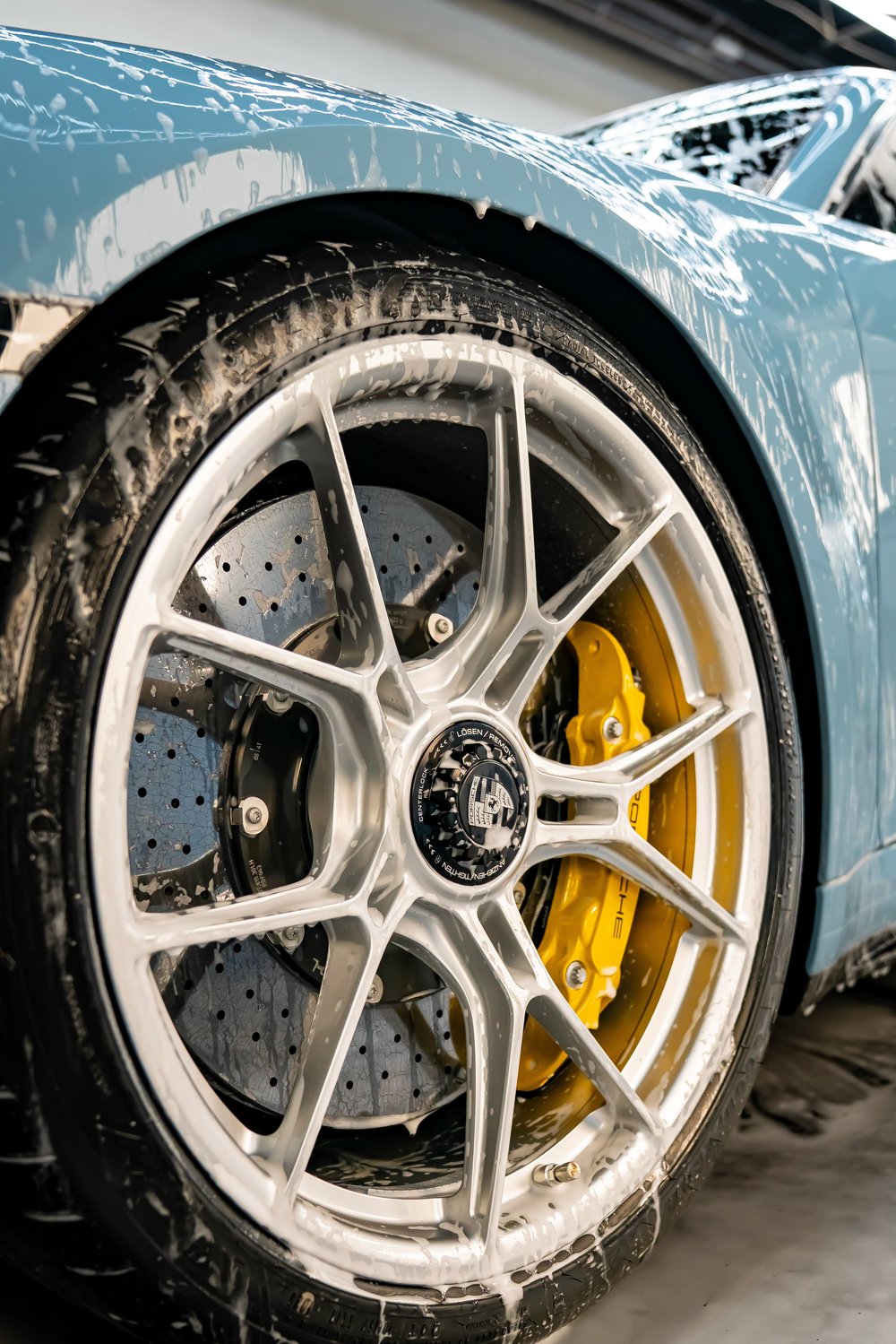 Foam brush cleaning an alloy wheel and brake caliper during an exterior decontamination wash